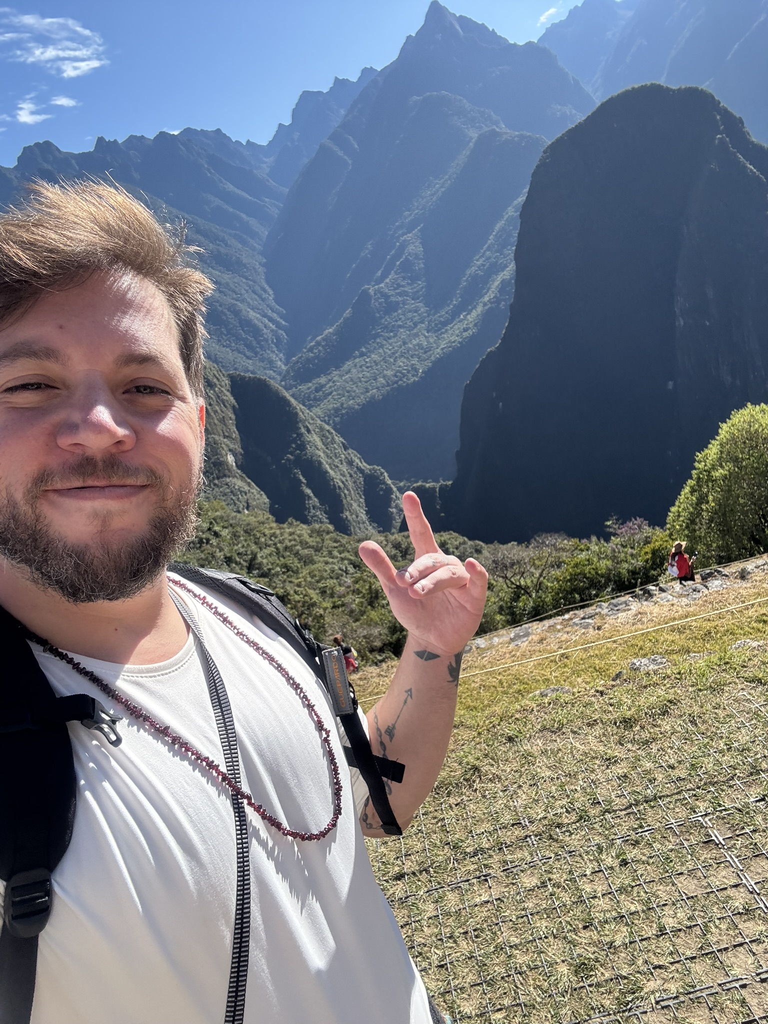 Selfie at Machu Picchu summit — mountains behind, smiling, mala beads